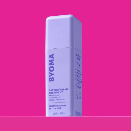 Un flacon de BYOMA Barrier+ Repair Treatment, vue en angle montrant les étapes de la routine "Boost Your Barrier" sur le panneau latéral, sur fond rose.