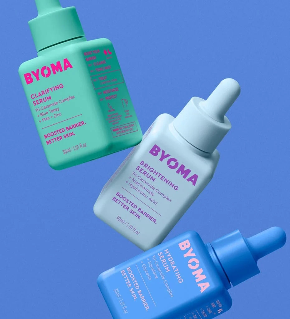 Des sérums BYOMA dans des flacons verts, blancs et bleus flottant sur un fond bleu.